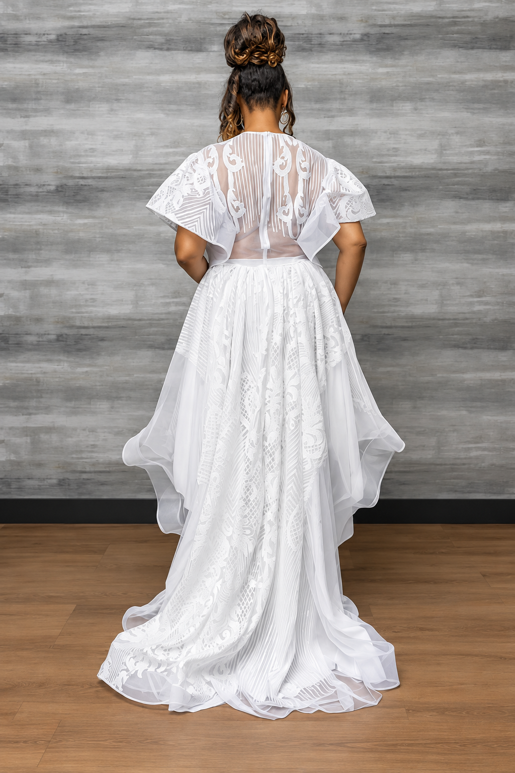Back view of the white lace and organza gown, showing the open back and cascading train