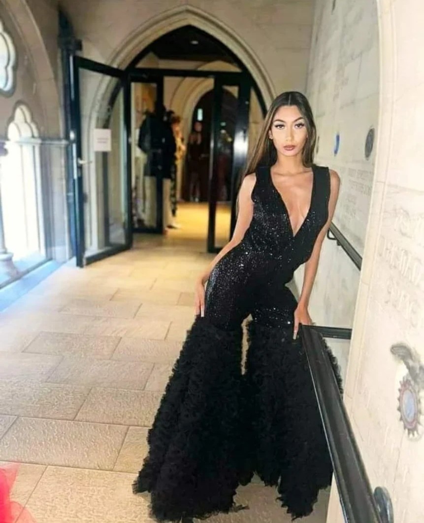 Model in the sequin ruffle bell bottom jumpsuit in a stone hallway