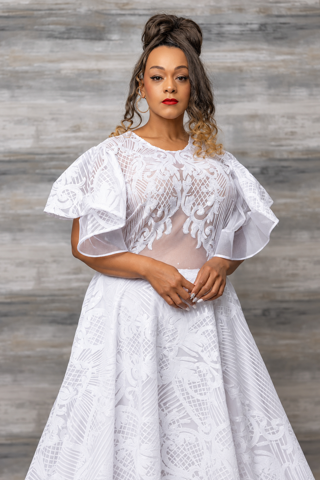 Model in a sheer white lace gown with fluttered organza sleeves and a sweeping embroidered organza skirt, shown from the front